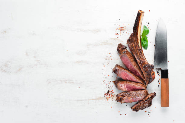 istock Steak on the bone. tomahawk steak On a white wooden background. Top view. Free copy space. 1059835570