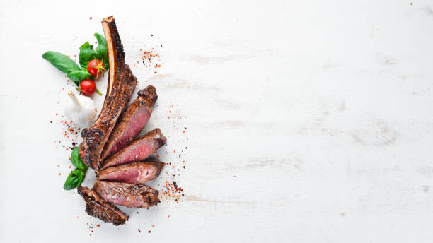 istock Steak on the bone. tomahawk steak On a white wooden background. Top view. Free copy space. 1059835610