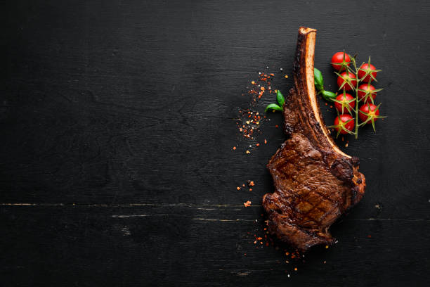 istock Steak on the bone. tomahawk steak On a black wooden background. Top view. Free copy space. 1059836034