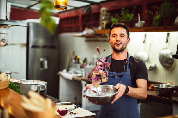 action portrait of male chef tossing ingredients in bowl - cooking process imagens e fotografias de stock