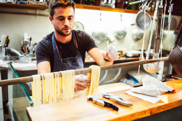 istock Male chef making spaghetti in kitchen and drying it on wooden pole 1059836126