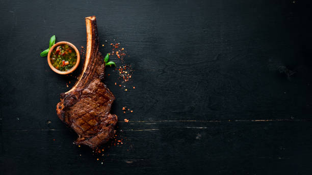 istock Steak on the bone. tomahawk steak On a black wooden background. Top view. Free copy space. 1059836138