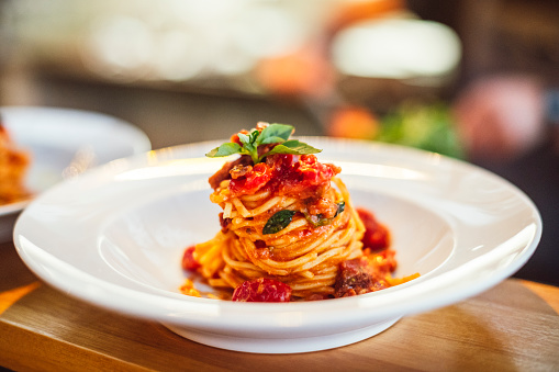Dish of handmade spaghetti and tomato, waiting on service counter of small restaurant, garnish, moist, tower