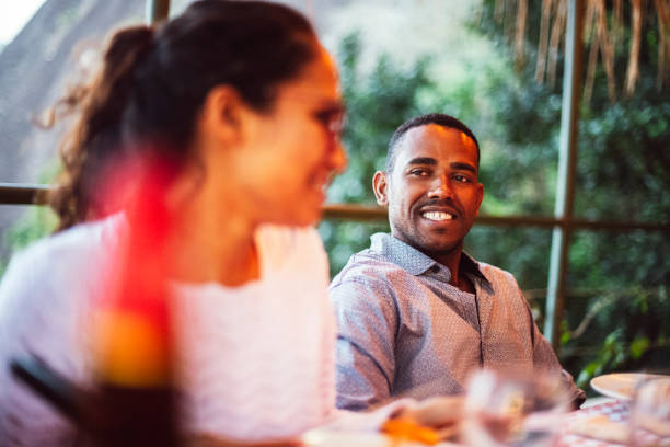 istock Smiling man sitting at restaurant table enjoying meal with friends 1059836300
