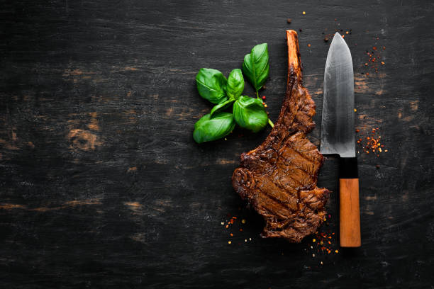 istock Steak on the bone. tomahawk steak On a black wooden background. Top view. Free copy space. 1059836424