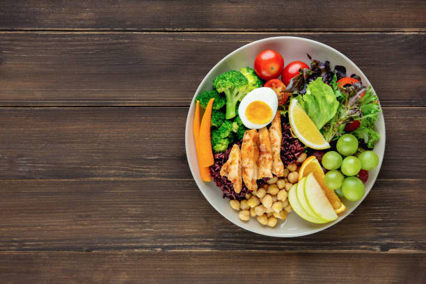 Clean food with mixed vegetable and fruit salad on wood table background Clean healthy low fat ready to eat food with mixed vegetable and fruit salad in round shape dish on wood table background top view with copy space sodium stock pictures, royalty-free photos & images