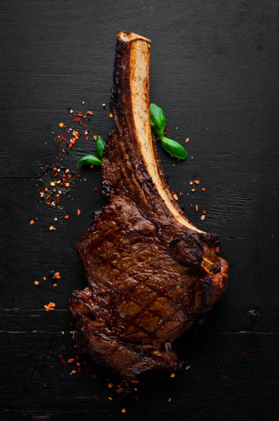 istock Steak on the bone. tomahawk steak On a black wooden background. Top view. Free copy space. 1059836822
