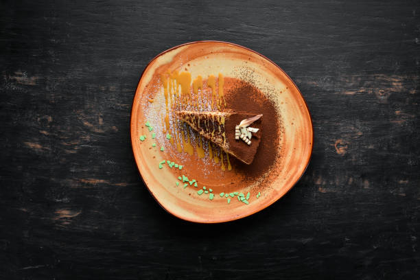 un pedazo de pastel de chocolate con caramelo. espartaco en un fondo de madera. vista superior. espacio de la copia gratuita. - spartacus fotografías e imágenes de stock