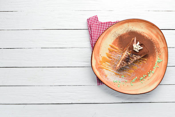 un pedazo de pastel de chocolate con caramelo. espartaco en un fondo de madera. vista superior. espacio de la copia gratuita. - spartacus fotografías e imágenes de stock