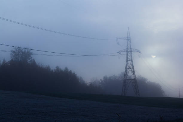 Electricity pylon in the fog during the morning hours stock photo