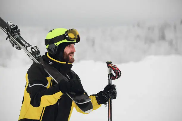 Portrait of a happy male skier in the alps with ski on shoulder
