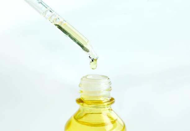 Dropping serum collagen moisturizer of face into clear yellow bottle soft light background. Protector skin Treatment facial essence oil, Vitamin C. Beauty and spa Concept.
