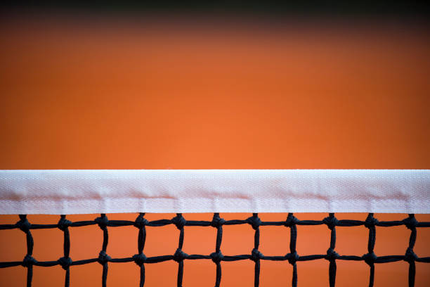 Tennis net and three balls on the clay court in background