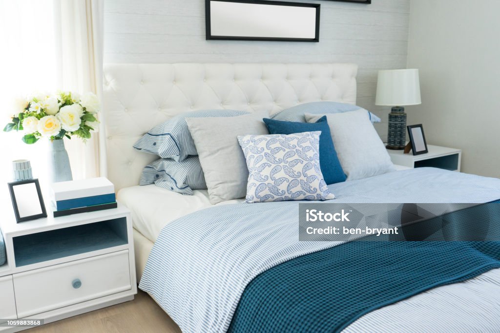 beach blue pillow on bed in bedroom beach blue pillow on bed with side table lamp in bedroom Bedroom Stock Photo