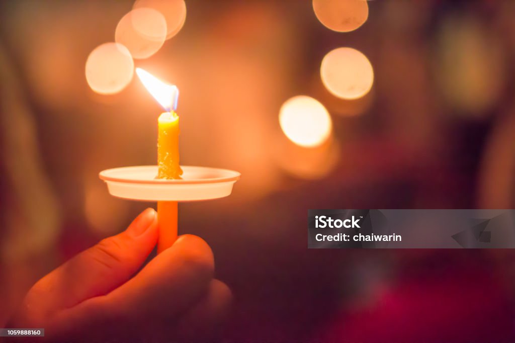 hand holding a burning candle with bokeh background Candle Stock Photo