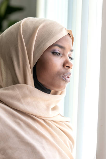 istock Concerned black muslim woman looking through a window 1059905700