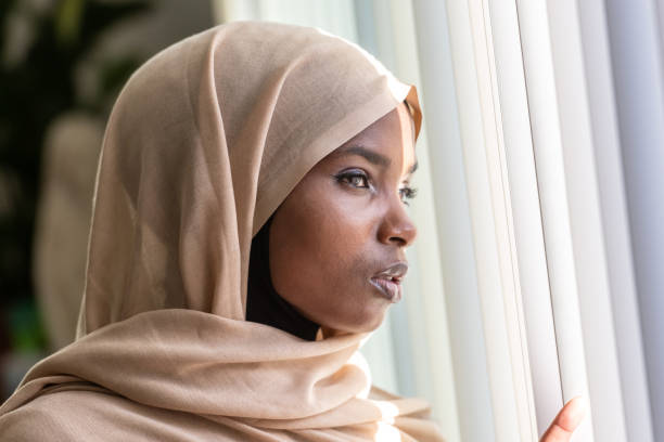 istock Concerned black muslim woman looking through a window 1059907238