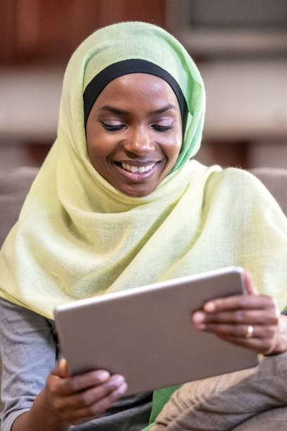 istock Smiling Muslim black young woman looking at her digital tablet 1059909512