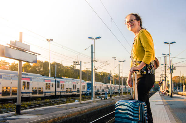 Elegant young woman with suitcase waiting for the train