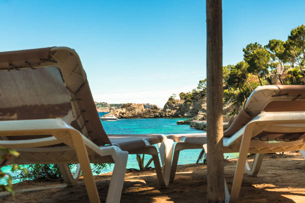 Relax on sun chairs with beautiful sea view of beach Cala Fornells on Majorca island, Spain Mediterranean Sea Idyllic sea view from two sun chairs of beautiful bay beach of Cala Fornells on Mallorca island, Mediterranean Sea Spain seaside views of cala fornells mallorca stock pictures, royalty-free photos & images