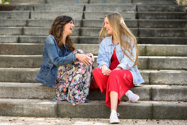 istock Two young women talking and laughing on urban steps 1059930668