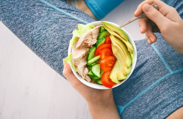 Young woman is resting and eating a healthy salad after a workout. stock photo