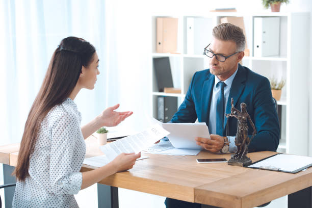 istock lawyer and client holding papers and discussing contract in office 1059944148