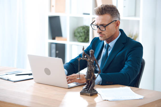 handsome lawyer in eyeglasses using laptop at workplace