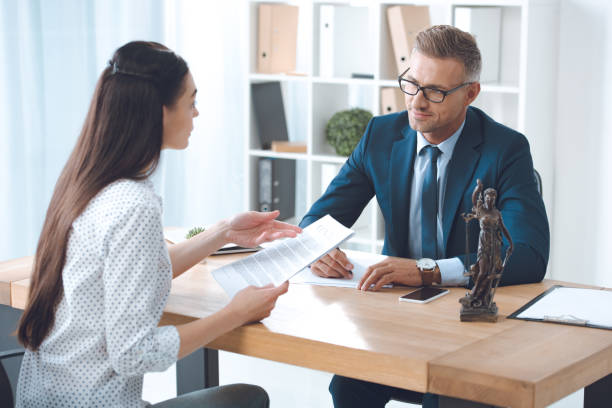 istock lawyer and client looking at each other while discussing papers in office 1059944250