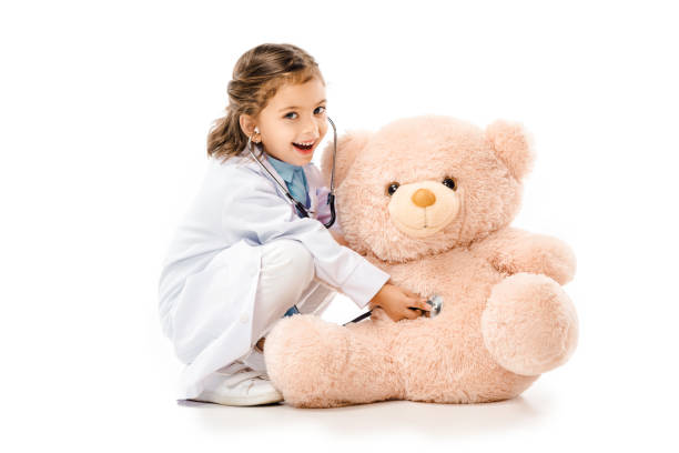 istock kid dressed in doctors white coat with stethoscope playing with teddy bear isolated on white 1059951156
