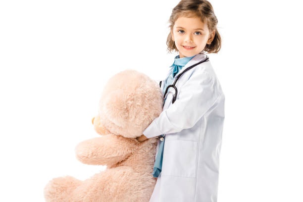 istock smiling kid dressed in doctors white coat with stethoscope holding big teddy bear isolated on white 1059951158