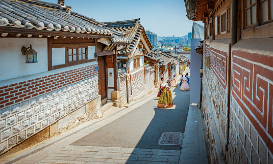 Seoul, South Korea - June 14, 2017: People dressing traditional Hanbok and traveling at Bukchon Hanok Village, Korean traditional village, The traditional village is composed of lots of alleys, hanok and is preserved to show a 600-year-old urban environment. Now it is used as a traditional culture center and hanok restaurant, allowing visitors to experience the atmosphere of the Joseon Dynasty.