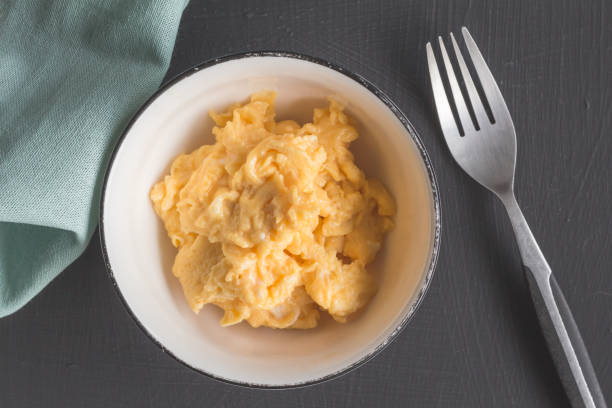 istock Moist scrambled eggs in bowl on black rustic table - Top view close up photo 1059951722