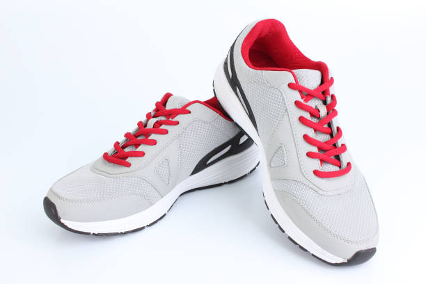 Gray sneakers with red laces on a white background stock photo