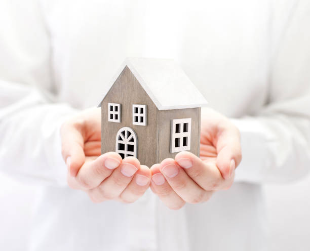 istock Small wooden toy house in hands 1059961016