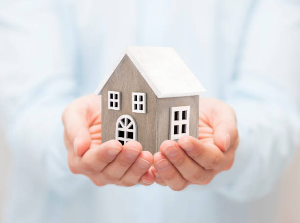 istock Small wooden toy house in hands 1059961038