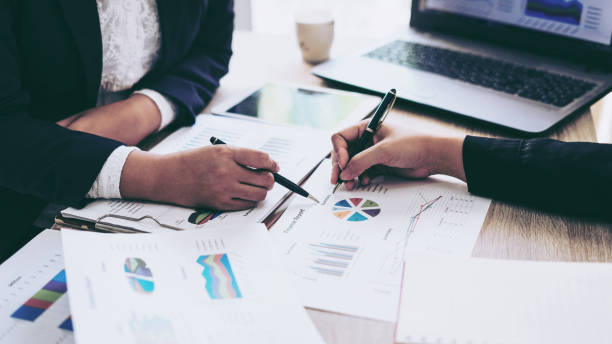 istock financial Image of two  business people pointing at business document presentation summary report , during discussion at meeting , Notebook on wood table 1059974318