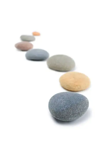Rounded stones arranged in a curving line on white background.