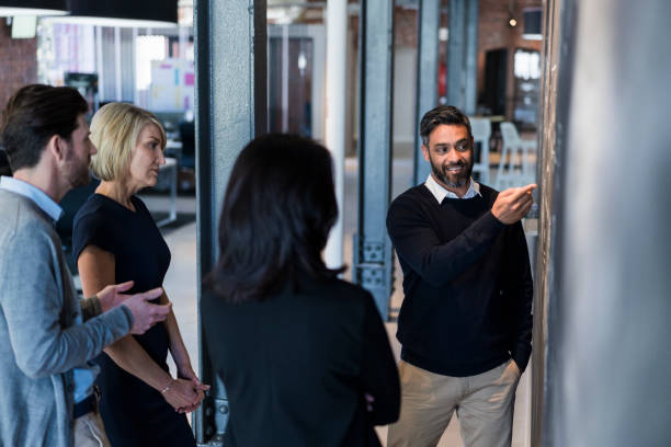 istock Coworkers discussing plan on blackboard in meeting 1060001160