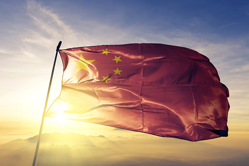 China Chinese flag on flagpole textile cloth fabric waving on the top sunrise mist fog