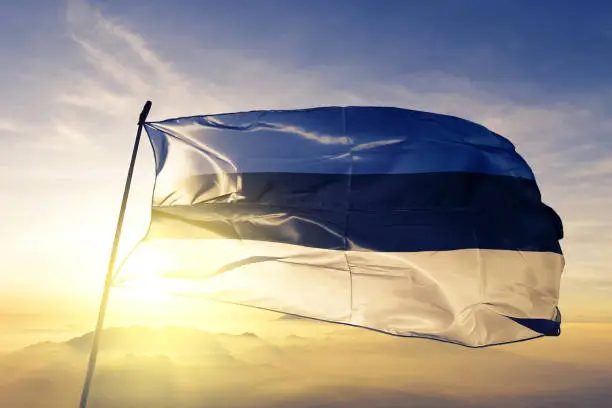 Photo of Estonia Estonian flag textile cloth fabric waving on the top sunrise mist fog