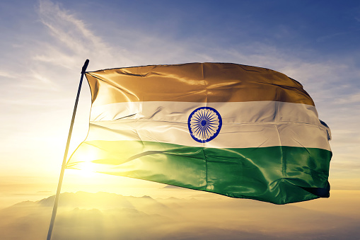 India Indian flag on flagpole textile cloth fabric waving on the top sunrise mist fog