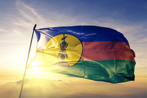 New Caledonia Caledonian flag textile cloth fabric waving on the top sunrise mist fog New Caledonia Caledonian flag on flagpole textile cloth fabric waving on the top sunrise mist fog new caledonia stock pictures, royalty-free photos & images
