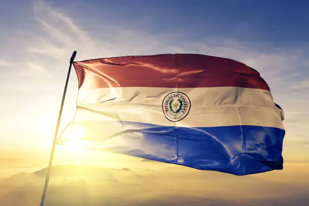 Photo of Paraguay Paraguayan flag textile cloth fabric waving on the top sunrise mist fog