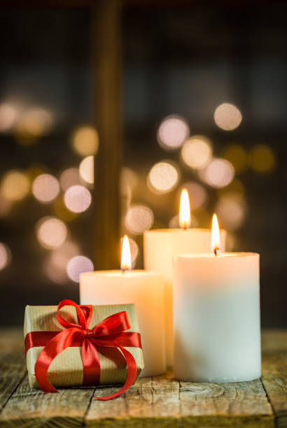 istock Christmas candles and gift on wooden table with blurred lights background 1060012630