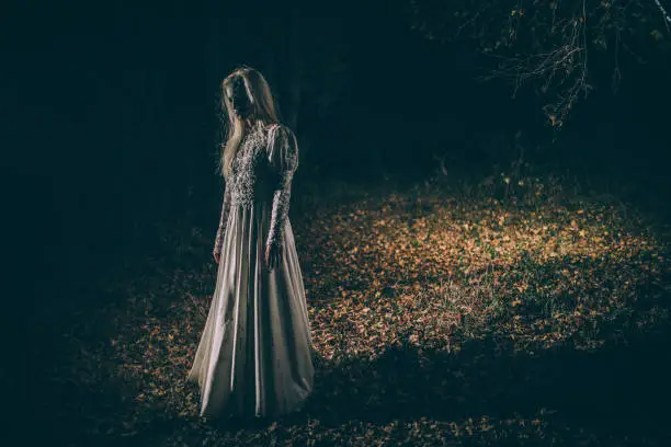 Woman dressed as witch standing in the night