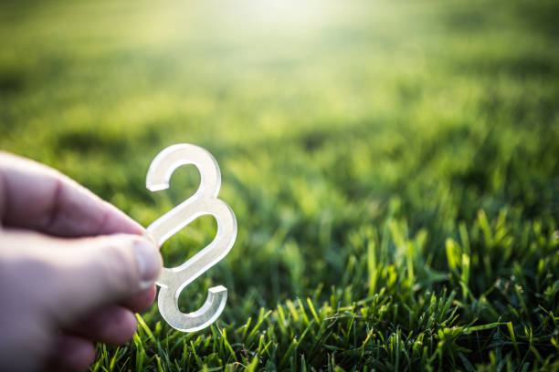 Hand holding paragraph symbol over green grass