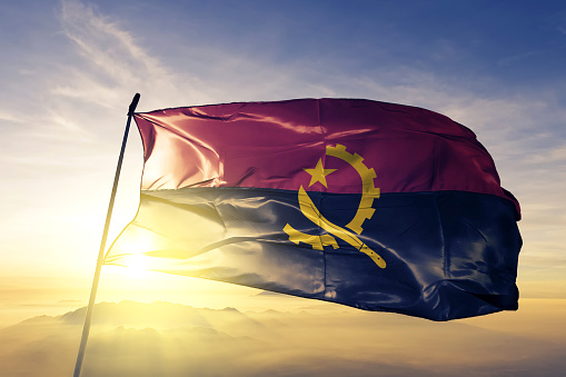 Angola Angola bandera tela tela ondeando en la niebla de la niebla de amanecer superior photo