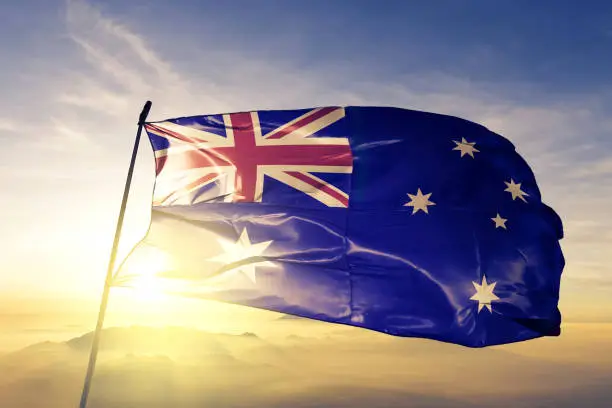 Photo of Australia Australian flag textile cloth fabric waving on the top sunrise mist fog