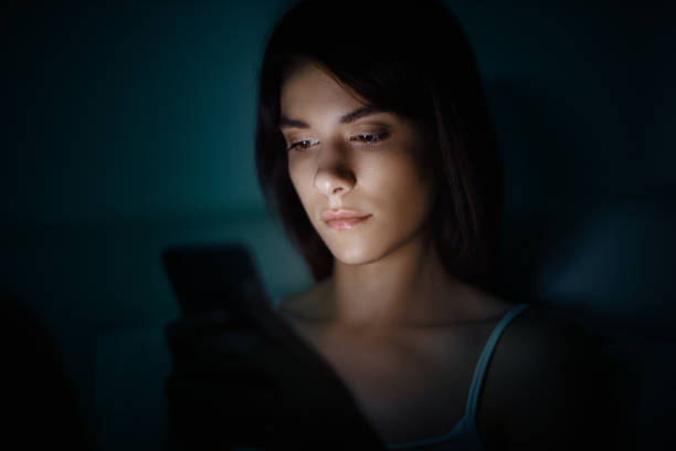 Woman in bed with smartphone stock photo